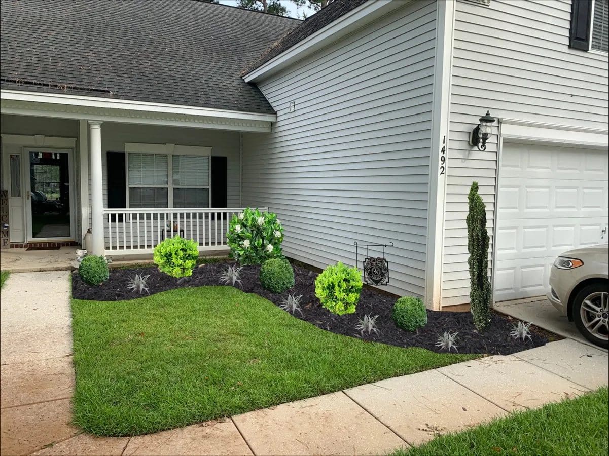 Well-maintained front yard with landscaped flower bed, green lawn, and modern single-family home