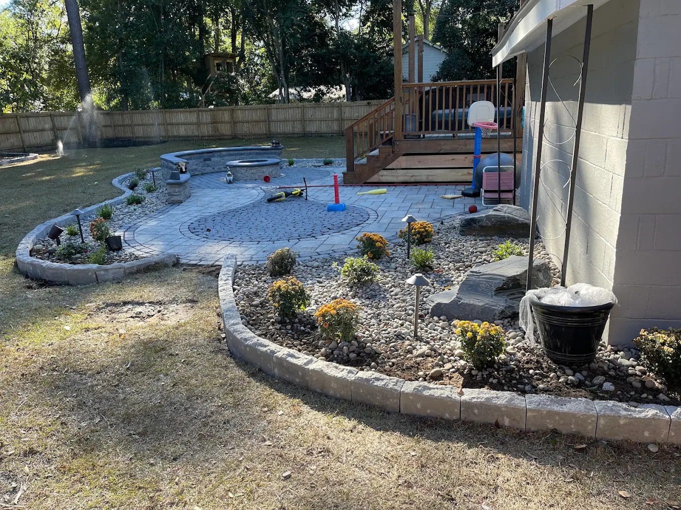 Backyard patio with blue pavers, pool, deck, landscaping, and playground equipment