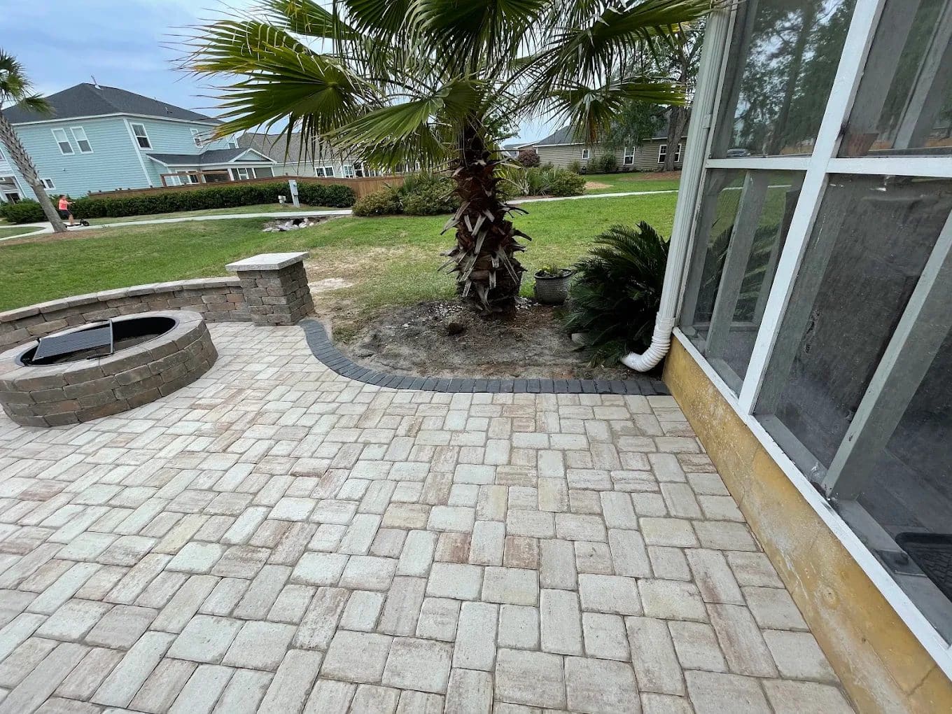 Paver patio with fire pit and palm trees in residential backyard