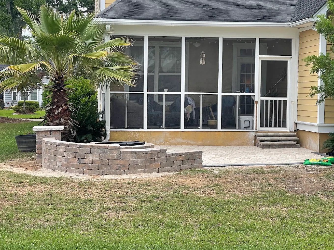 Screened patio with paver surface, brick planter, and palm tree landscaping